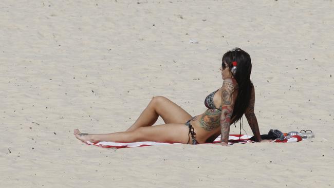 A tattooed woman sunbakes on a sunny Bondi beach on a beautiful Autumn day. Generic.