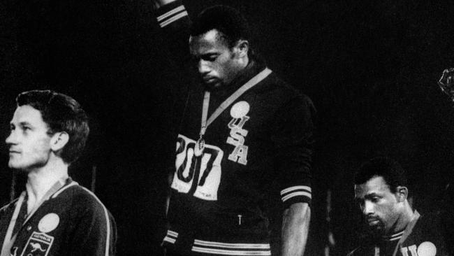 (FILES) US athletes Tommie Smith (C) and John Carlos (R) raise their gloved fists in the Black Power salute to express their opposition to racism in the USA during the US national anthem, after receiving their medals for first and third place in the men's 200m event at the 1968 Mexico Olympic Games in Mexico City on October 17, 1968, at left is Peter Norman of Australia who took second place. Like all utopias, the Olympic ideal has often collided with reality: bombings, boycotts and takeovers by dictatorial regimes are as much a part of the history of the Games as the exploits and records of the champions. The exclusion of Russia and Belarus from Paris-2024 and the exceptional security measures taken because of the risk of an attack are just the latest avatars in the tumultuous relationship between the Olympic Games and world geopolitics, which has existed almost since the Games were refounded in 1896. (Photo by EPU / AFP)