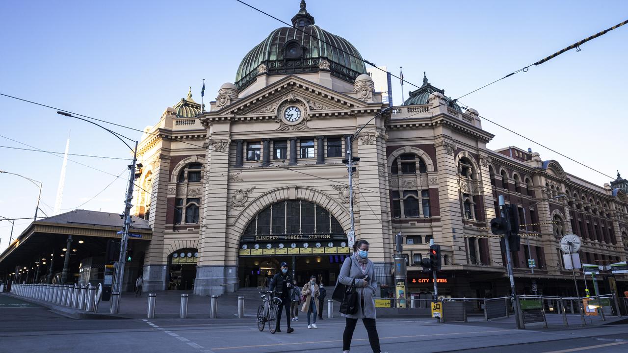 People wear face masks cross a quiet Flinders Street. Picture: Daniel Pockett/Getty Images