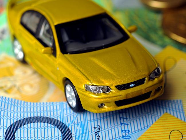 How to cut your car costs - Toy matchbox cars pictured with piles of money. Coins and notes arranged as roads and obstacles for the toy cars to drive over.