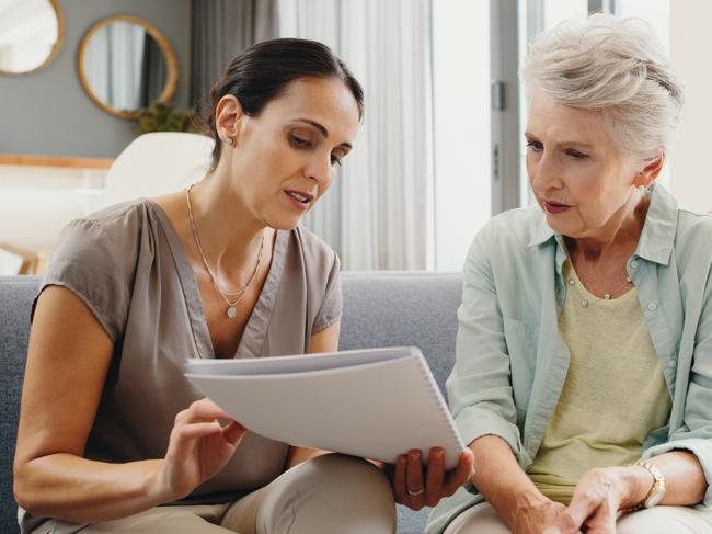 Caregiver talking to senior woman about insurance, support with finance documents and help reading retirement paperwork on the sofa in home. Girl helping elderly person with Alzheimer care at house