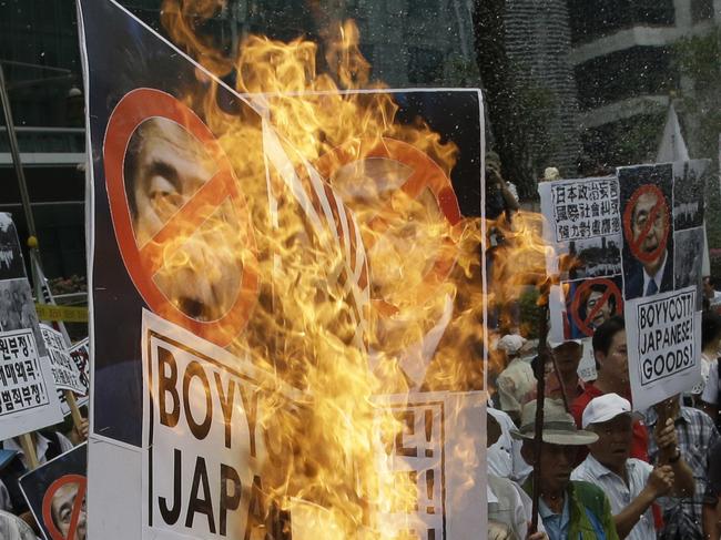 A South Korean protester burns defaced images of Japanese Prime Minister Shinzo Abe during a rally denouncing Abe's statement to mark the 70th anniversary of the end of World War II, near the Japanese Embassy in Seoul, South Korea, Saturday, Aug. 15, 2015. Abe acknowledged that Japan inflicted "immeasurable damage and suffering" on innocent people in the war, but stopped short of offering his own apology, drawing criticism from China and South Korea. (AP Photo/Lee Jin-man)