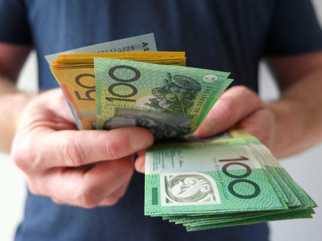 A man counting Australian dollar bills. A picture that describes buying, paying, handing out money, or showing money. Australian cash money generic