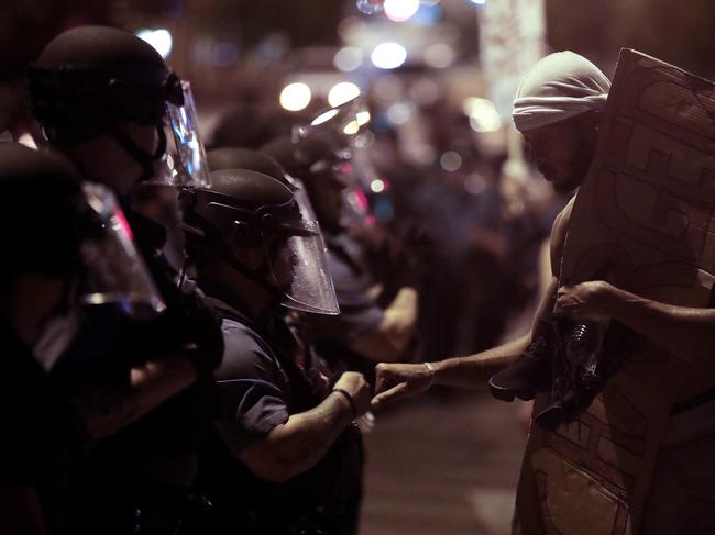 A protester fist bumps police in riot gear in Kansas City. Picture: Charlie Riedel