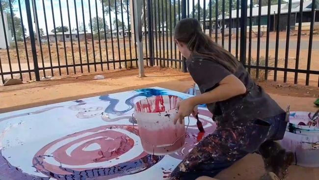 Stills taken from video where a non-indigenous employee is seen contributing to a painting by (Indigenous) artist Yaritji Young.