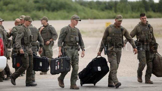 Canadian armed tactical police carry weapons and ballistics shields onto an aircraft in Gillam, Canada. Picture: Clint Brewer