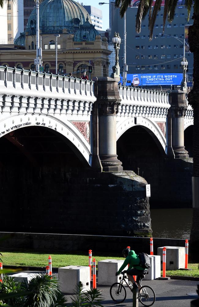 A cyclist weaves their way under Princes Bridge’s bollard wall. Picture: Nicole Garmston