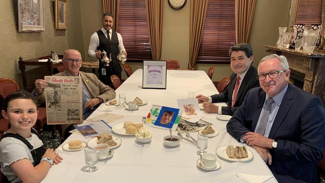 Robert Stark, holding an old copy of the Manly Daily featuring him on the front page when he was a police dog handler, with his granddaughter Ruby, 9, at a lunch at Parliament House with the State MP for Wakehurst Brad Hazzard (right) and Acting Seniors Minister Geoff Lee. Picture: Supplied