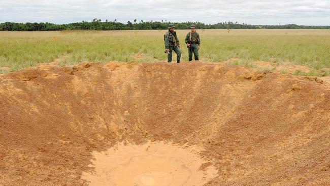 Venezuelan National Guard soldiers by a crater exploded into a clandestine drug airstrip in Apure. Picture: Leo Ramirez