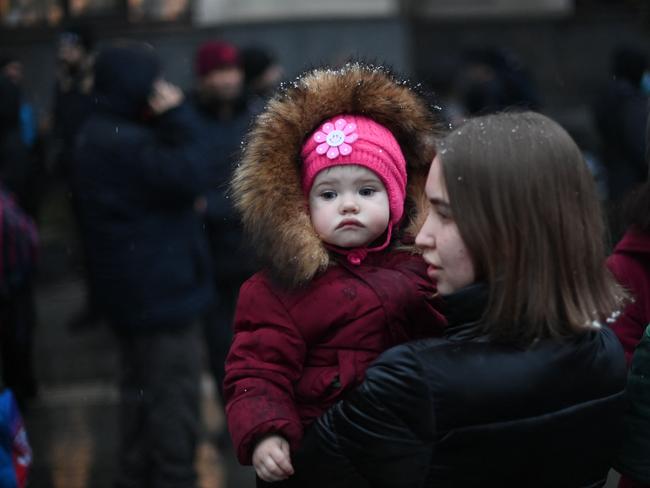 A young woman holds a child as they stand outside a train station in Lviv. Picture: AFP