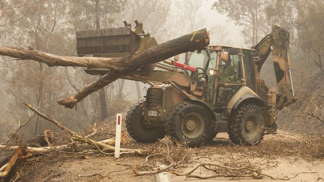 The defence force uses a backhoe to help clear fire-damaged trees from the Great Alpine Road between Bairnsdale and Omeo. Picture: Department of Defence