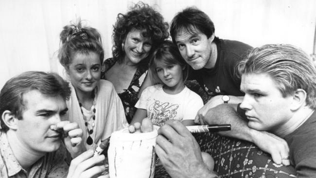 Flashback: Sarah Monahanis is visited in her home in 1990 by Hughes and the cast after breaking her leg in a car accident.