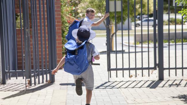 Two school children running out the school gate at the end of the day.