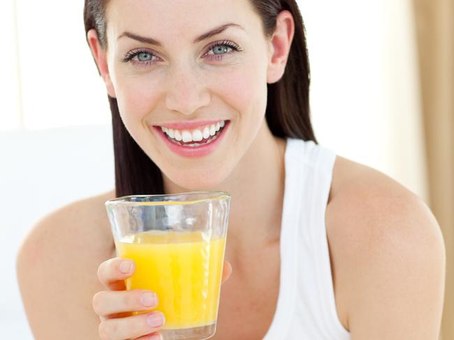 Smiling woman drinking orange juice, morning