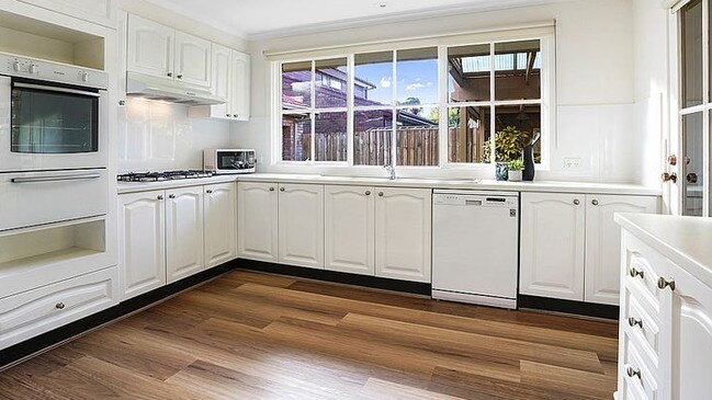 A glossy stone kitchen boasting gas appliances including a five burner gas cooktop, an oven, dishwasher and lots of counter space.