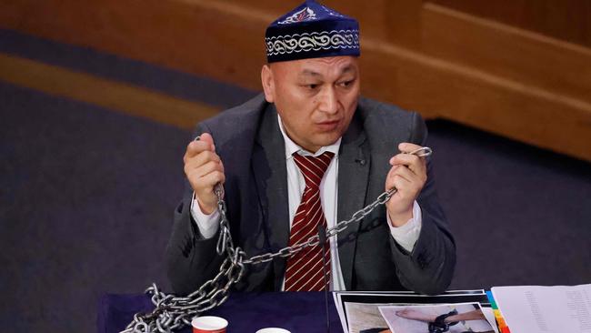 Witness Kazakh-Uighur Omir Bekali demonstrates how he says he was shackled in chains at a re-education camp as he speaks on the first day of hearings. Picture: Tolga Akmen / AFP