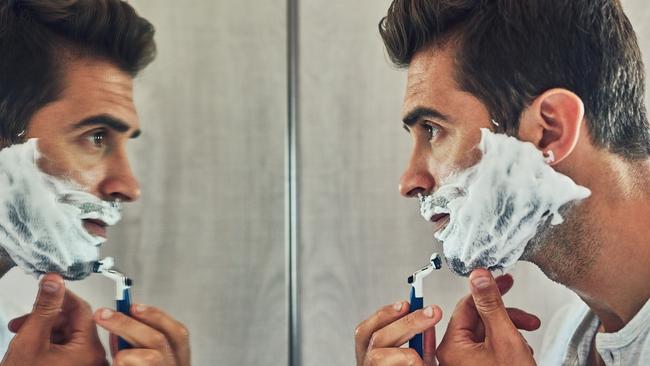 Shot of a focused young man shaving his beard while looking at his reflection in the mirror at home. Picture: File