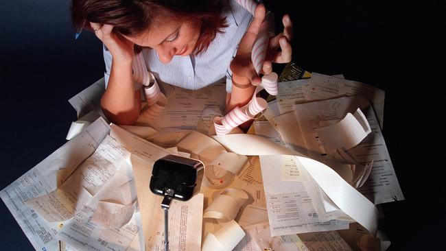 Woman stressed out filing tax return surrounded by receipts and bank statements. /Income/tax