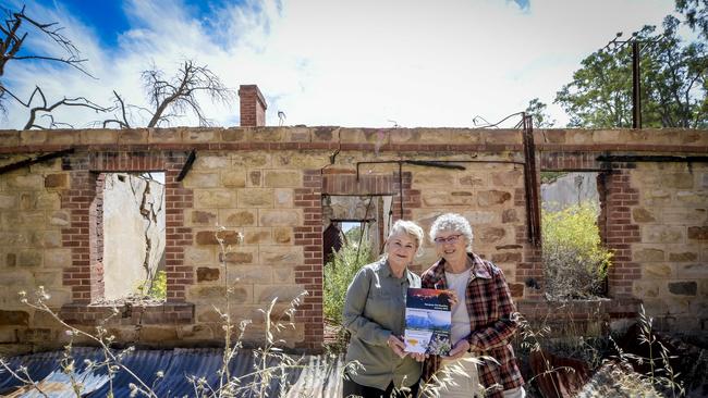 Denise Elland and Jan Verrall with their new book ‘Sampson Flat Bushfire, January 2015, A History: 100 Individual Accounts of Lessons Learned’, pictured at a burnt ruin. Picture: Roy VanDerVegt