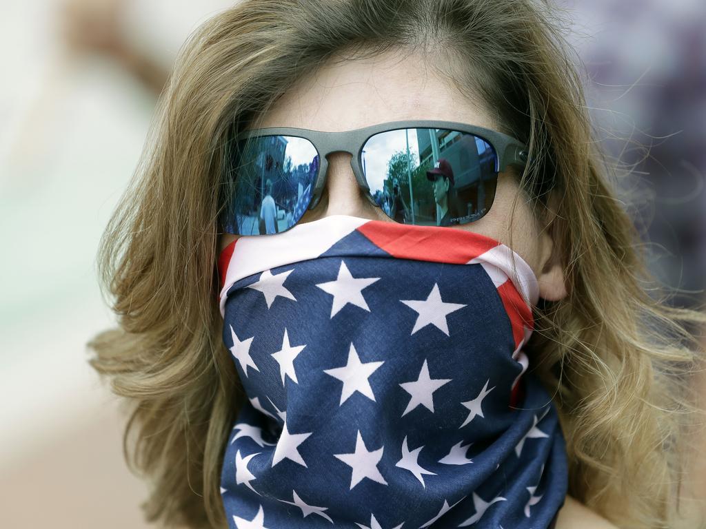 A woman wearing a US flag to cover his face at a rally in Florida, where some want the lockdown to end. Picture: AP Photo/John Raoux