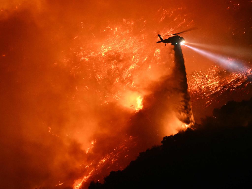 A fire fighting helicopter drops water on the Palisades fire. Picture: Patrick T. Fallon / AFP