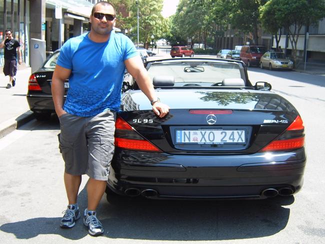 Ayik posing with one of his many flashy cars.