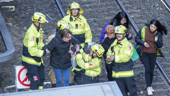 Passengers are escorted by emergency services along the light train rail line after being trapped by a fallen tree. Picture: NewsWire / Jeremy Piper