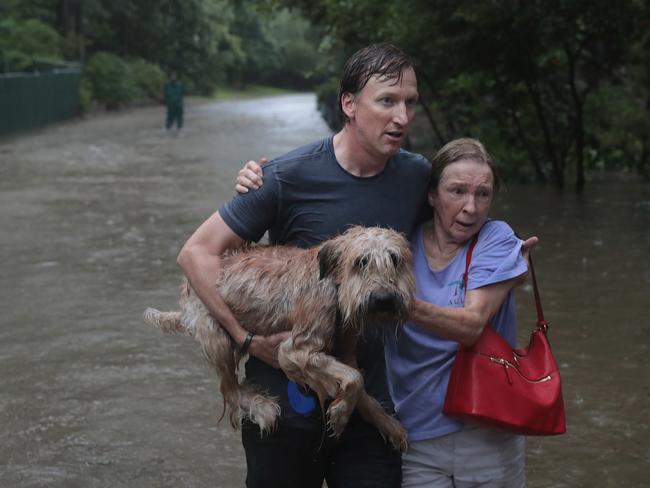 Andrew White helps a neighbor down a street after rescuing her from her home in his boat in the upscale River Oaks neighborhood after it was inundated with flooding from Hurricane Harvey on August 27, 2017 in Houston, Texas. Harvey, which made landfall north of Corpus Christi late Friday evening, is expected to dump upwards to 40 inches of rain in Texas over the next couple of days. Picture: AFP