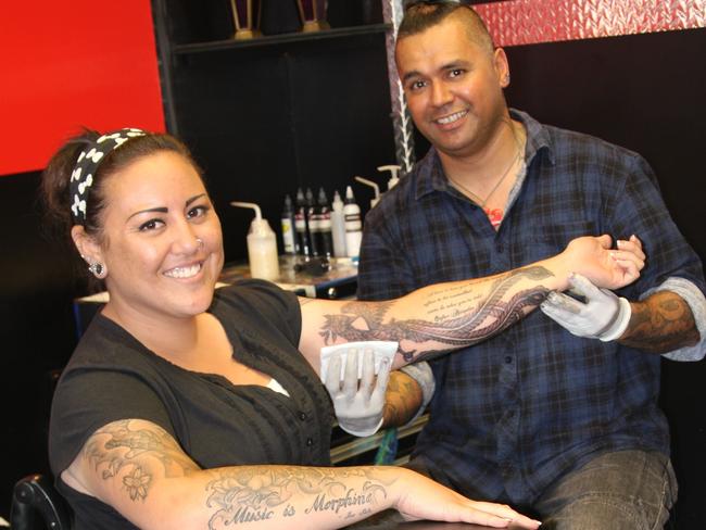 Tattoo Artist Chrash tattoos a phoenix on Heidi's arm.