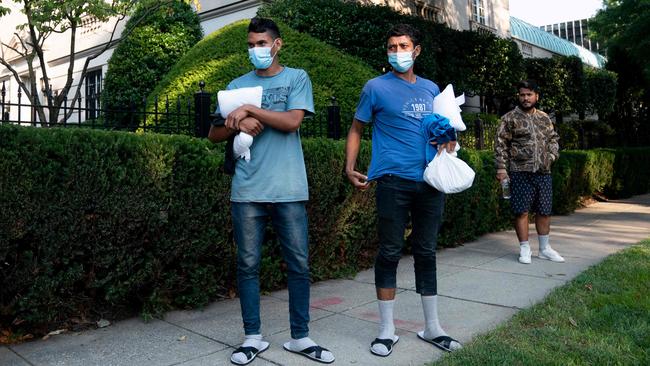 Migrants from Venezuela wait to be transported to a local church by volunteers after being dropped off outside US Vice President Kamala Harris’s home. Picture: AFP