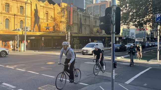 Cyclists and traffic on Exhibition St in the morning peak.