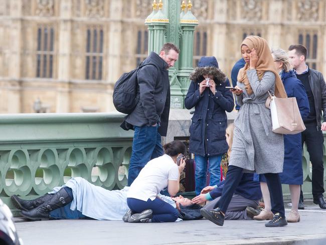 This picture of a Muslim woman walking past one of the injured has drawn criticism online. It is not known if she had been helping victims prior to this shot being taken. Picture: REX/Shutterstock/australscope