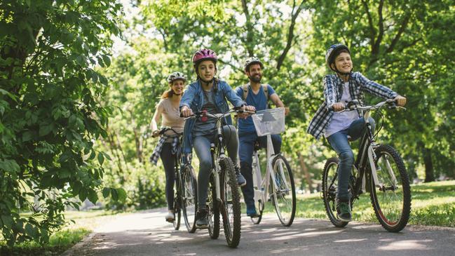 Family riding bicycle in the public park together. Cycling and enjoying the sunny day