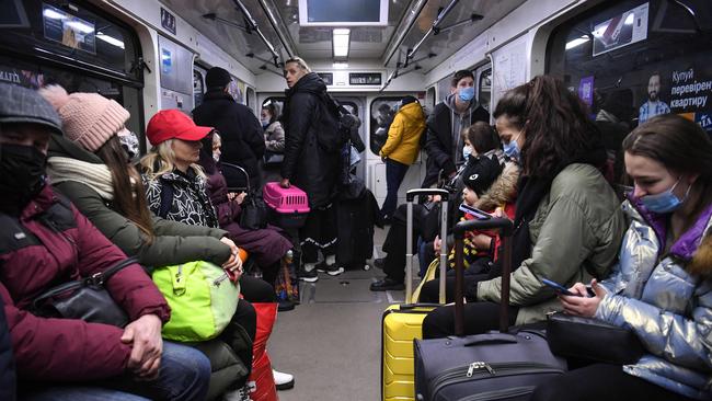 People, some carrying bags and suitcases, sit in a metro in Kyiv in the morning of February 24 following military strikes by Russia.