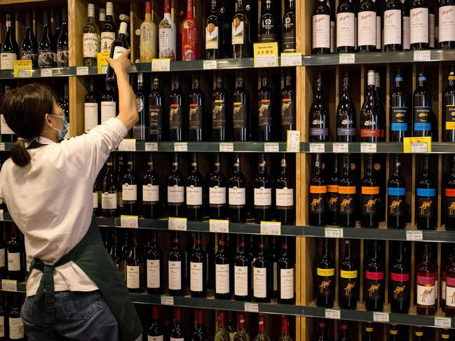 An employee works as Australian-made wine (on display shelves on R) are seen for sale at a store in Beijing on August 18, 2020. - China on August 18 ramped up tensions with Australia after it launched a probe into wine imports from the country, the latest salvo in an increasingly bitter row between the trade partners. (Photo by NOEL CELIS / AFP)