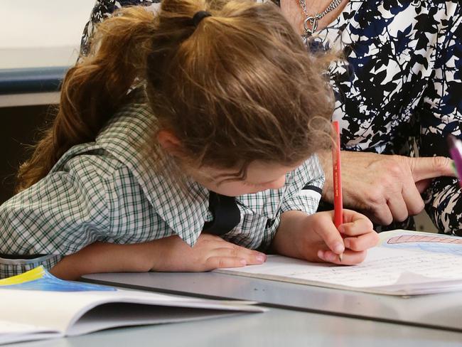 Teacher Monique Dickson poses with students Penny Waterhouse, 6, and Annabelle Pitt, 6, from class 1G at St MartinÕs Catholic Primary School in Carina, Brisbane on Friday, September 21, 2018. The Catholic schools system in Queensland is the first non-government education authority to roll out phonics screening for Year 1 students. Photo: Claudia Baxter