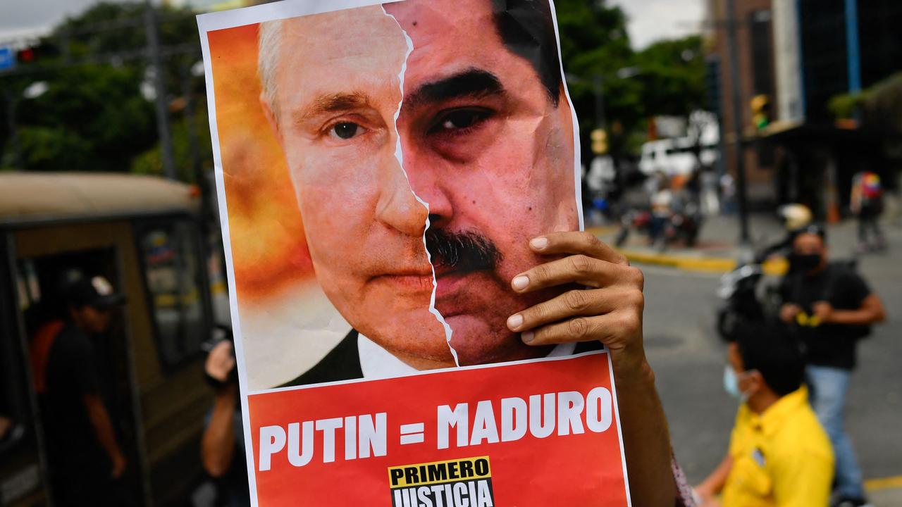 An activist member of Opposition party Primero Justicia holds a placard showing the face of Russian President Vladimir Putin and Venezuelan President Nicolas Maduro. Picture: Federico Parra/AFP