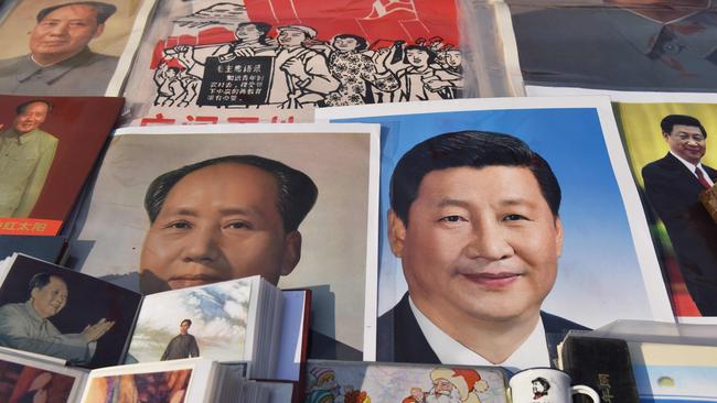 Posters of Chinese President Xi Jinping (R) and late communist leader Mao Zedong are seen at a market in Beijing on February 26.