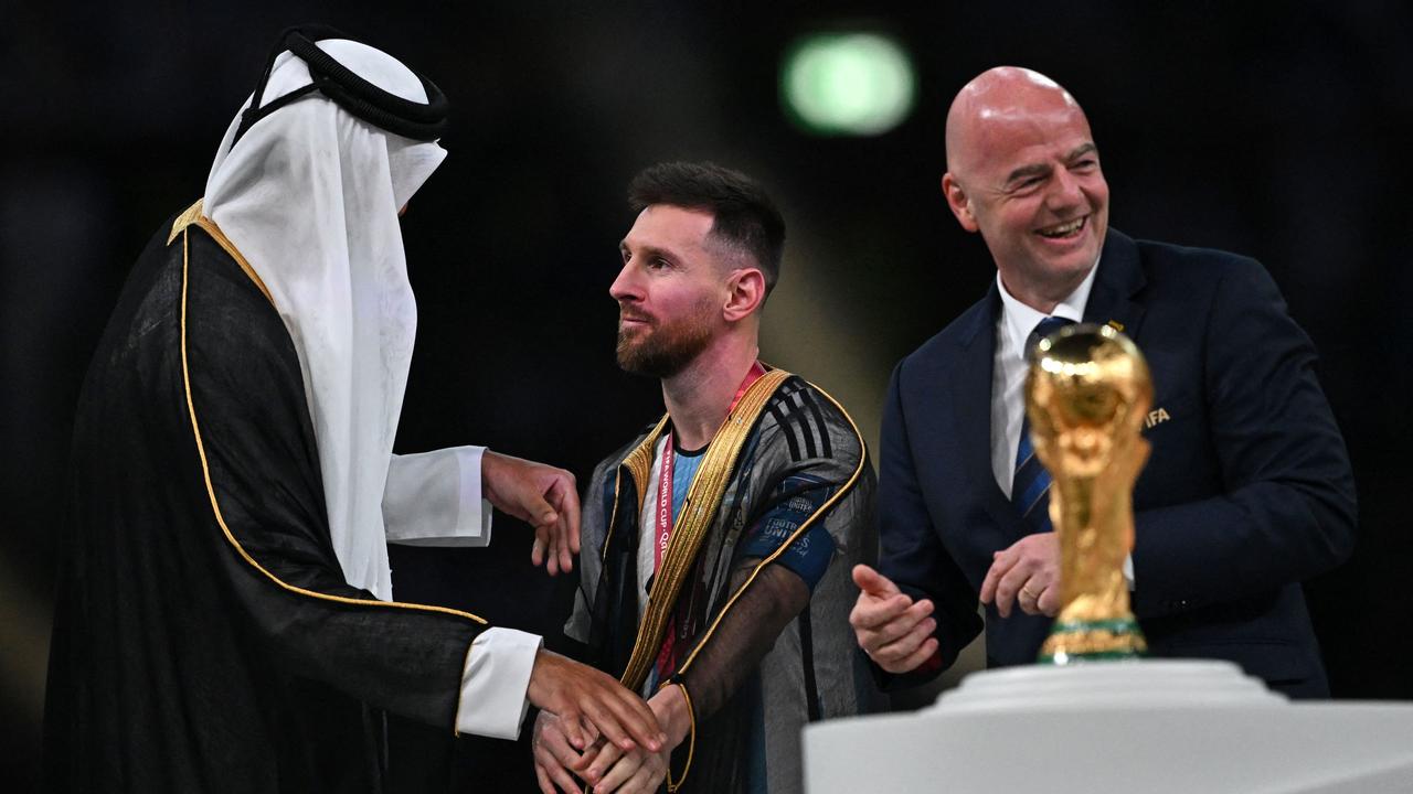 Argentina's forward #10 Lionel Messi (C) shakes hands with Qatar's Emir Sheikh Tamim bin Hamad al-Thani (L) next to FIFA President Gianni Infantino as he stands on stage by the FIFA World Cup Trophy after Argentina won the Qatar 2022 World Cup final football match between Argentina and France at Lusail Stadium in Lusail, north of Doha on December 18, 2022. (Photo by Paul ELLIS / AFP)