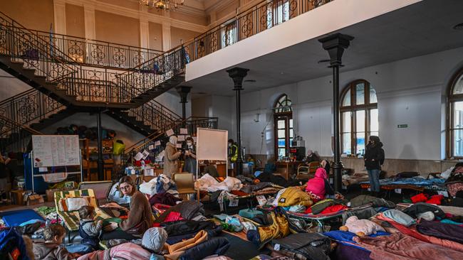 People who fled the war in Ukraine rest inside the old train station building that has been converted for a temporary refugee shelter in Krakow, Poland. Picture: Getty