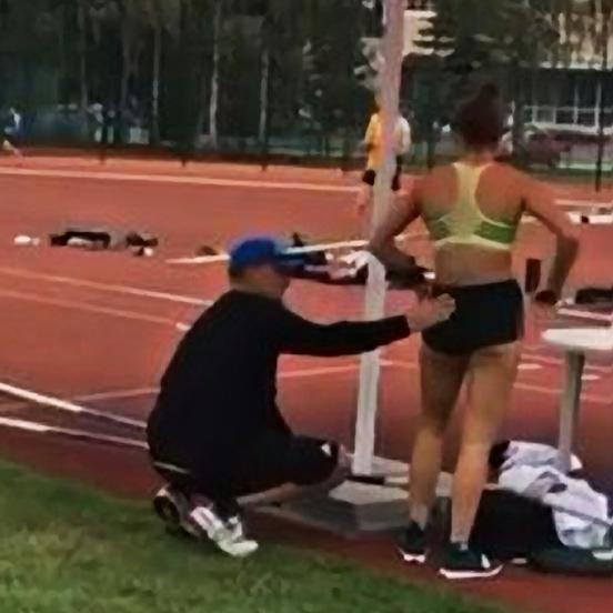 Coach Alex Parnov seen touching pole vaulter Nina Kennedy.