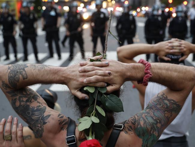 Protesters kneel in front of New York City Police Department officers before being arrested for violating curfew beside the iconic Plaza Hotel. Picture: AP