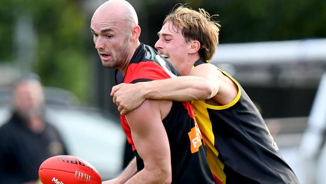 Joshua Grabham of Riddell handballs whilst being tackled during the round two RDFNL Bendigo Bank Seniors match between Riddell and Kyneton at Riddells Creek Recreation Reserve, on April 13,2024, in Diggers Rest, Australia. (Photo by Josh Chadwick)