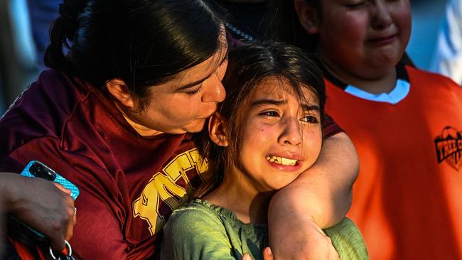 Gabriella Uriegas, a soccer teammate of Tess Mata who died in the shooting, cries while holding her mother Geneva Uriegas as they visit a makeshift memorial outside the Uvalde County Courthouse in Texas. (Photo by CHANDAN KHANNA / AFP)