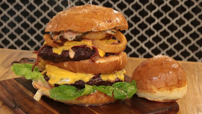 The giant OMG Burger sits next to a normal sized bun. Pictures: Robert Pozo