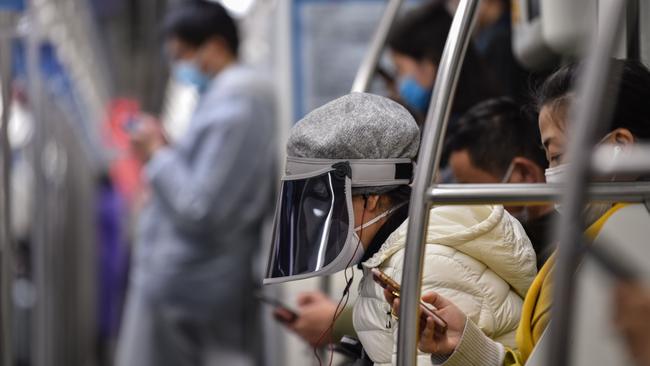 A woman wearing a face cover riding a subway train in Shanghai, China.