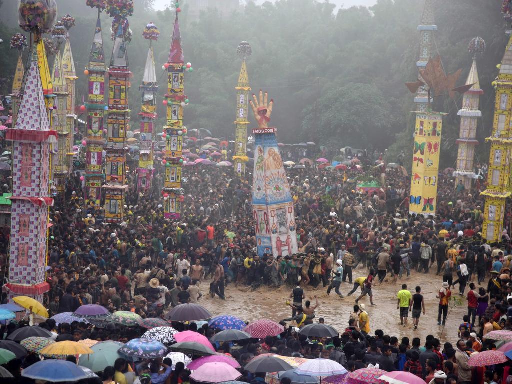 Indian spectators watch as Pnar, or Jaintia, tribesmen pull a Rong - chariot - and dance in muddy waters during the celebration of the Behdienkhlam festival in Tuber village, in the northeastern state of Meghalaya on July 21, 2016. Behdienkhlam, a traditional festival of the Pnars, is celebrated after sowing and seeks a good harvest and to drive away plague and diseases. Young men symbolically drive away evil spirits by beating the roof of every house with bamboo poles. / AFP PHOTO / Biju BORO