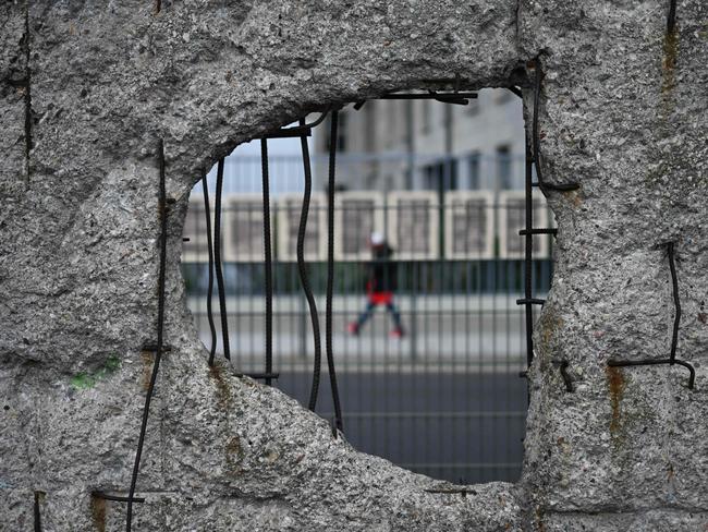 A pedestrian passes remaining parts of the Berlin Wall on the 34th anniversary of Germany's Unification, on October 3, 2024. (Photo by RALF HIRSCHBERGER / AFP)