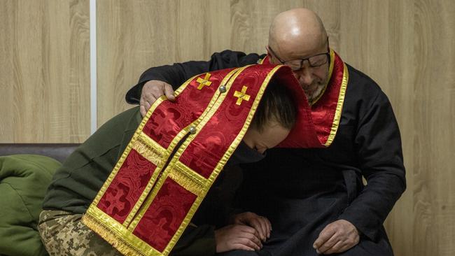 A woman from the Ukrainian military confesses to Territorial Defense unit chaplain and combat paramedic Yevhen ahead of her marriage ceremony, at a hospital in Brovary, Ukraine. Picture: Getty