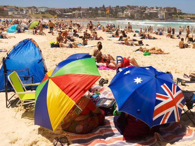 Sydney, Australia - December 31, 2013: Colourful umbrellas, tents, chairs and towels shade some beachgoers from the sun on New Year's Eve at Bondi Beach.